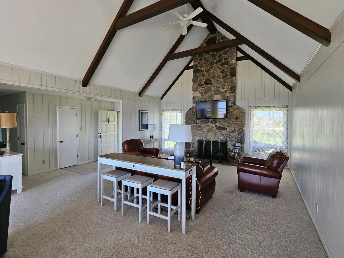 A cozy dining area anchored by a sturdy wooden dining table is complemented by leather chairs and a striking stone fireplace. Wooden beams overhead add a rustic charm, while the whole space is bathed in warm, inviting tones—suggesting a place where long, leisurely meals and memorable moments easily unfold.